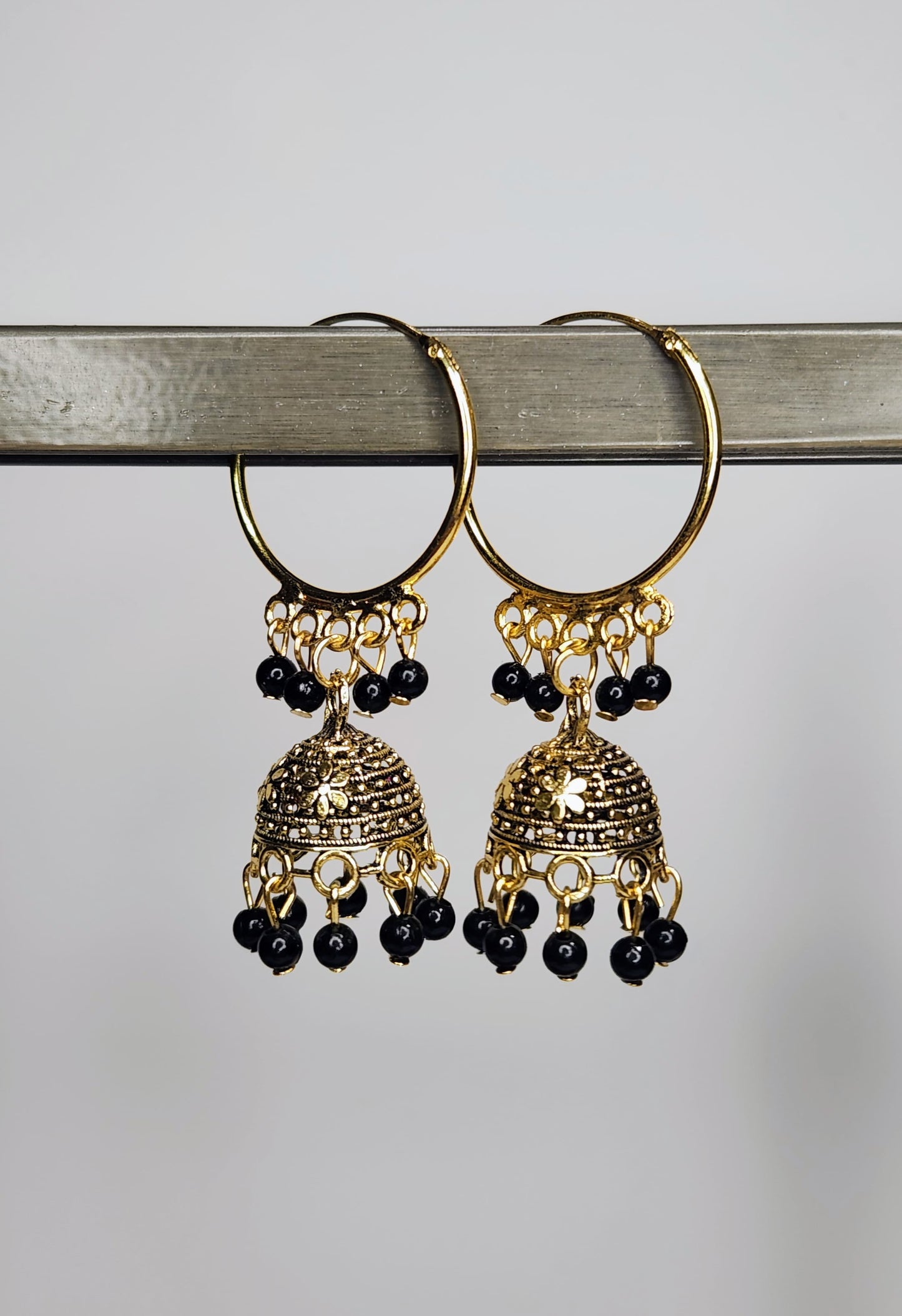 Gold hoop earrings with black beads on a gray background