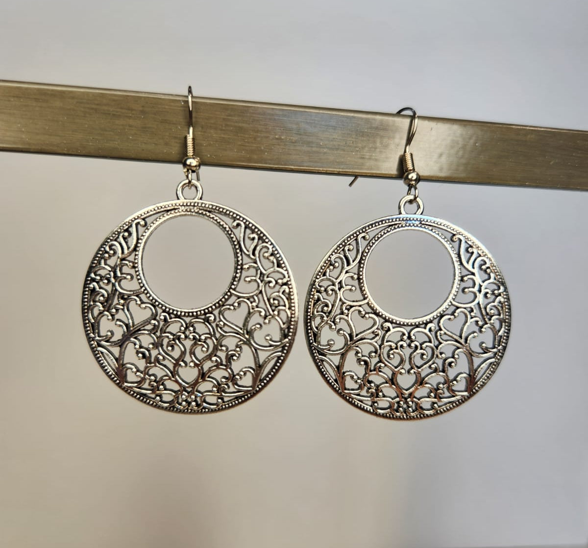 Pair of silver hoop earrings with intricate designs on a white background