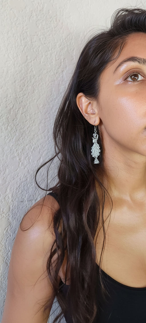 Pair of silver CLASSICAL DANCE earrings on a metallic stand.