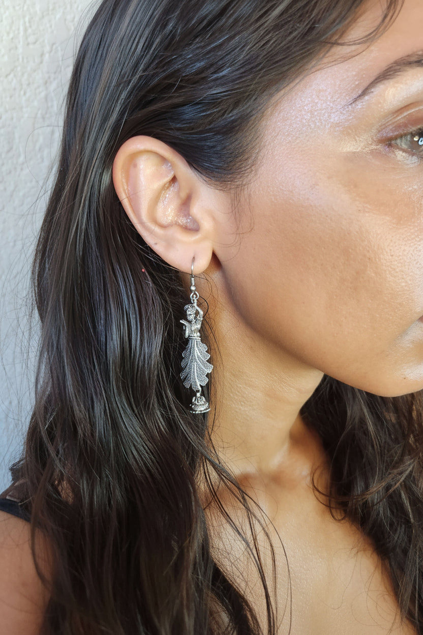 Pair of silver CLASSICAL DANCE earrings on a metallic stand.