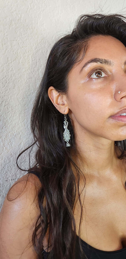 Pair of silver CLASSICAL DANCE earrings on a metallic stand.