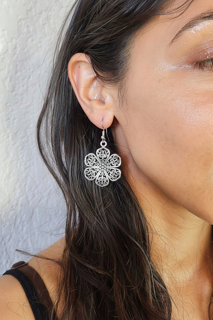 Close-up of a woman wearing a silver floral earring against a neutral background