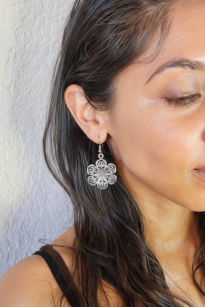 Close-up of a woman wearing a silver floral earring against a neutral background