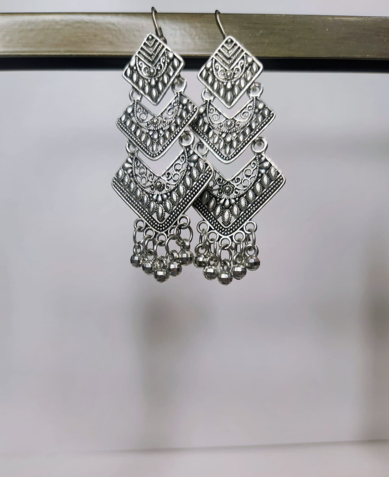 Pair of silver earrings with geometric design on a white background