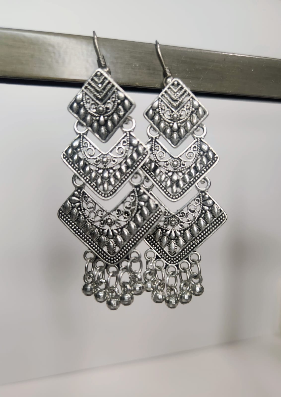 Pair of silver chandelier earrings on a metallic surface