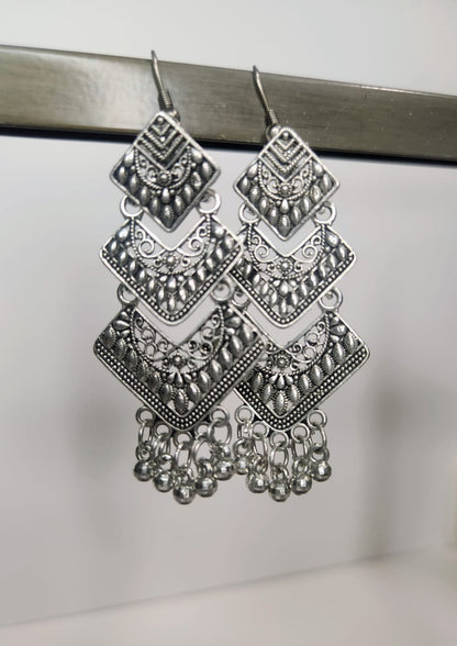 Pair of silver chandelier earrings on a metallic surface