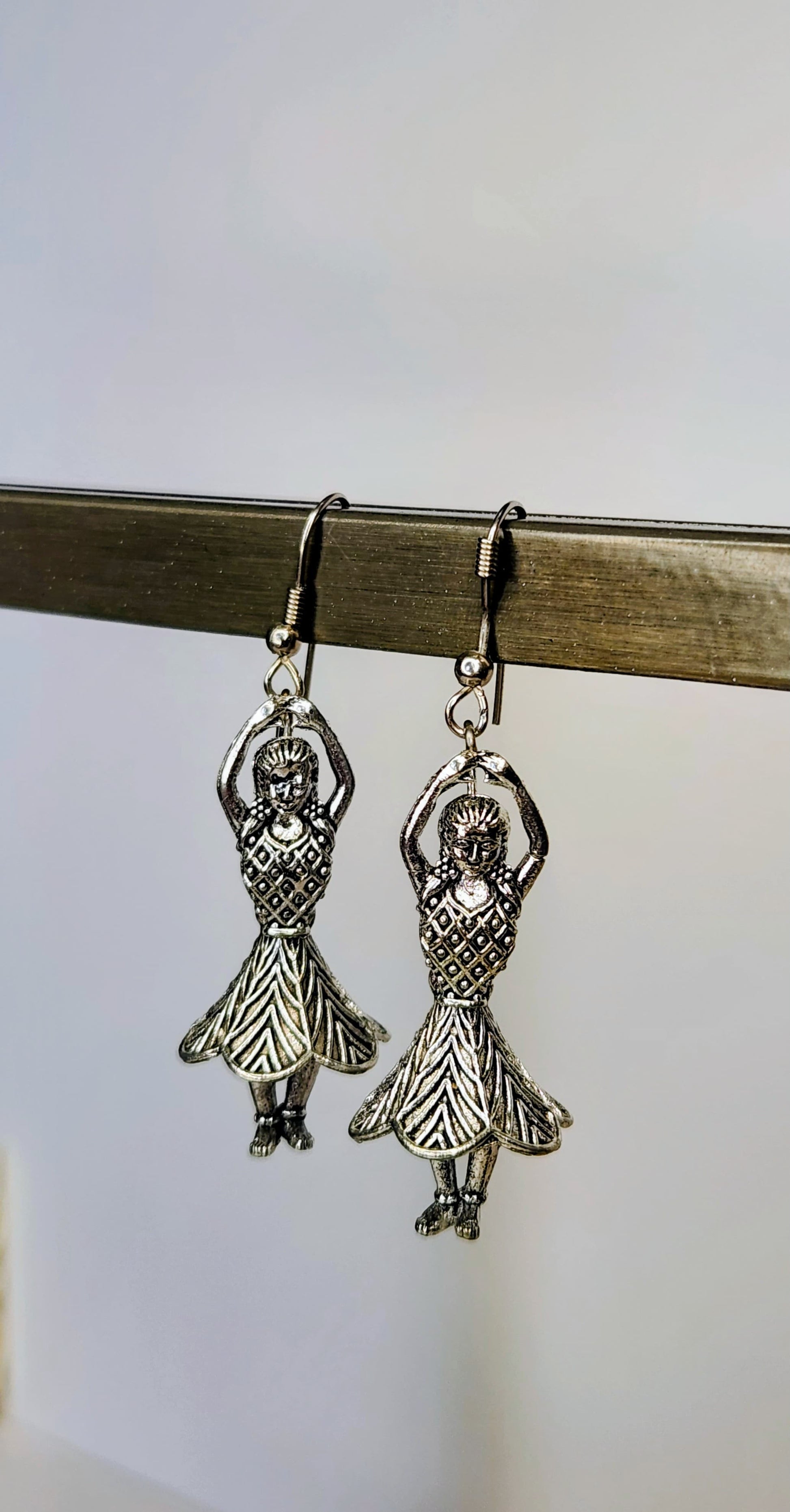 Silver dancing figure earrings on a white background