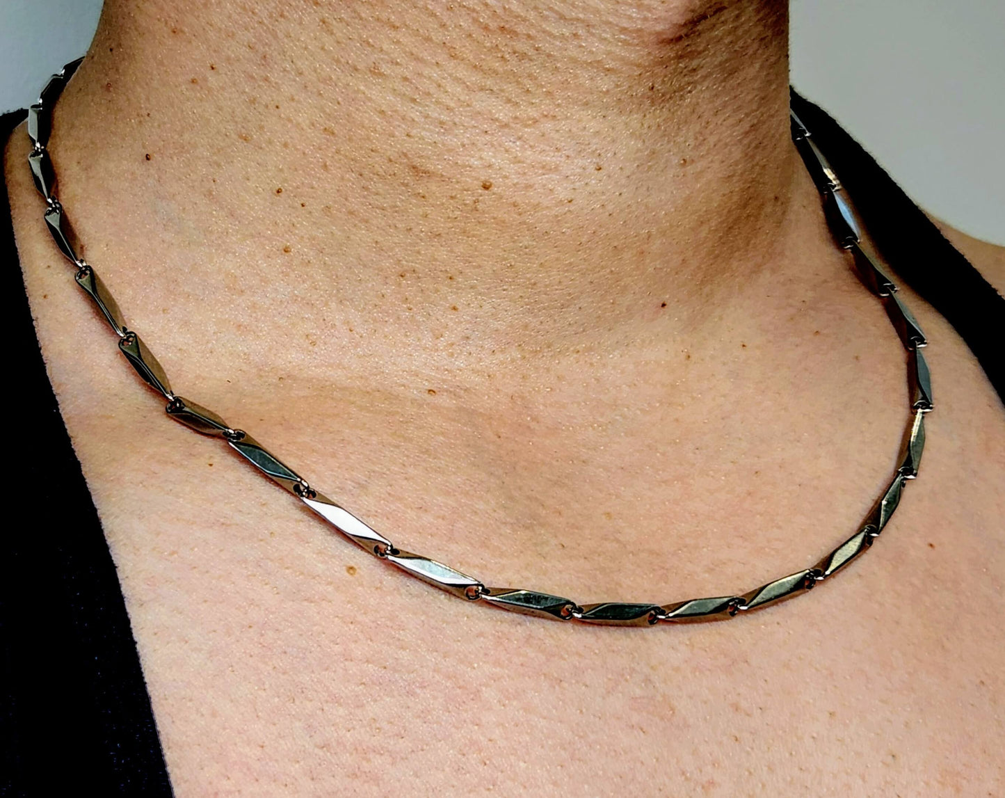 Necklace on a person's neck with a neutral background
