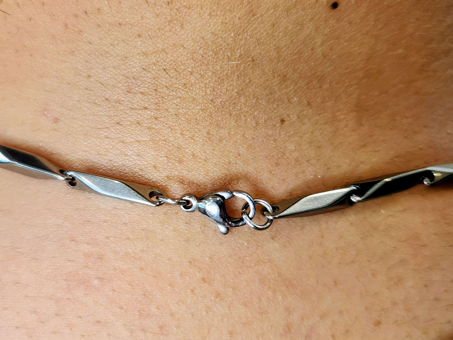 Silver bracelet on a person's wrist with a close-up view of the skin and bracelet.