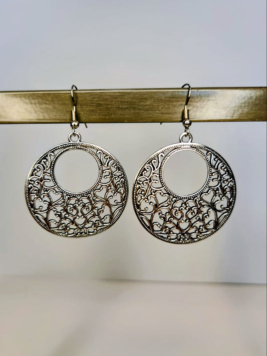 Pair of silver filigree hoop earrings on a gold stand.
