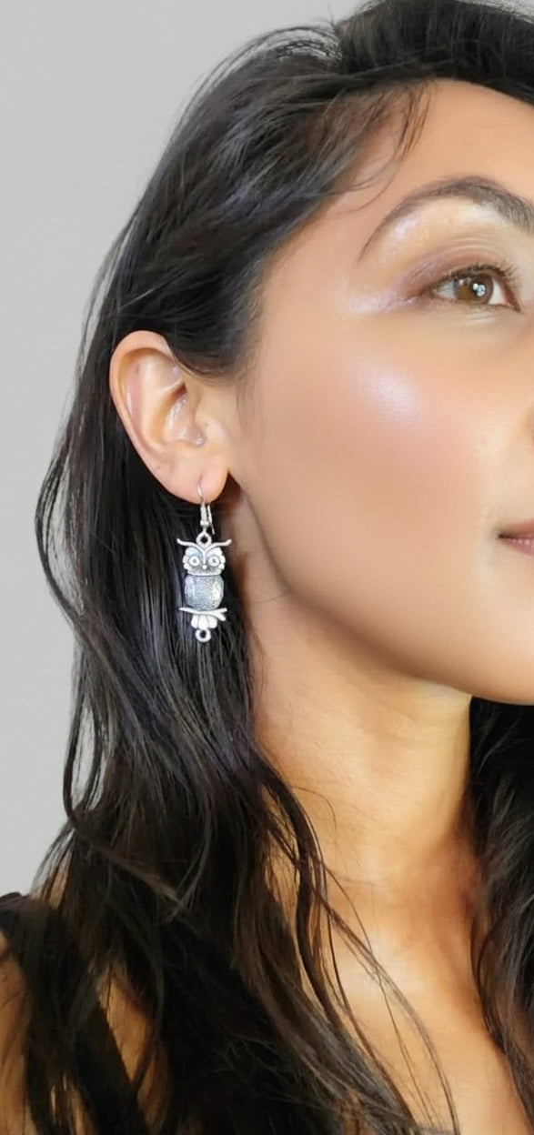Close-up of a person wearing silver earrings with a neutral background