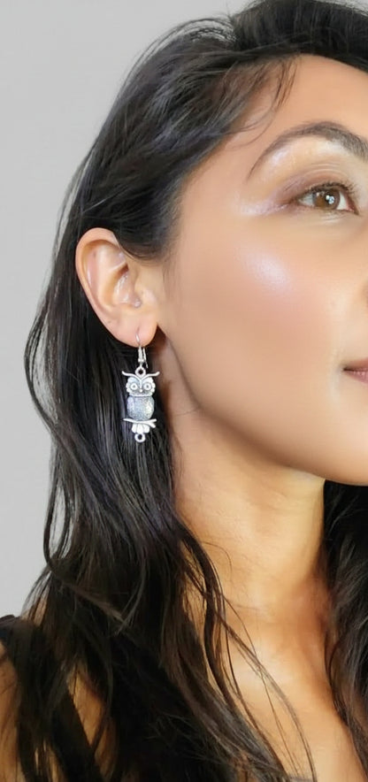 Close-up of a person wearing silver earrings with a neutral background