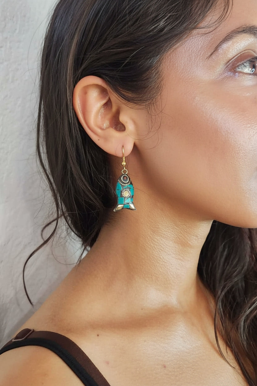 Close-up of a woman wearing a turquoise earring with a neutral background