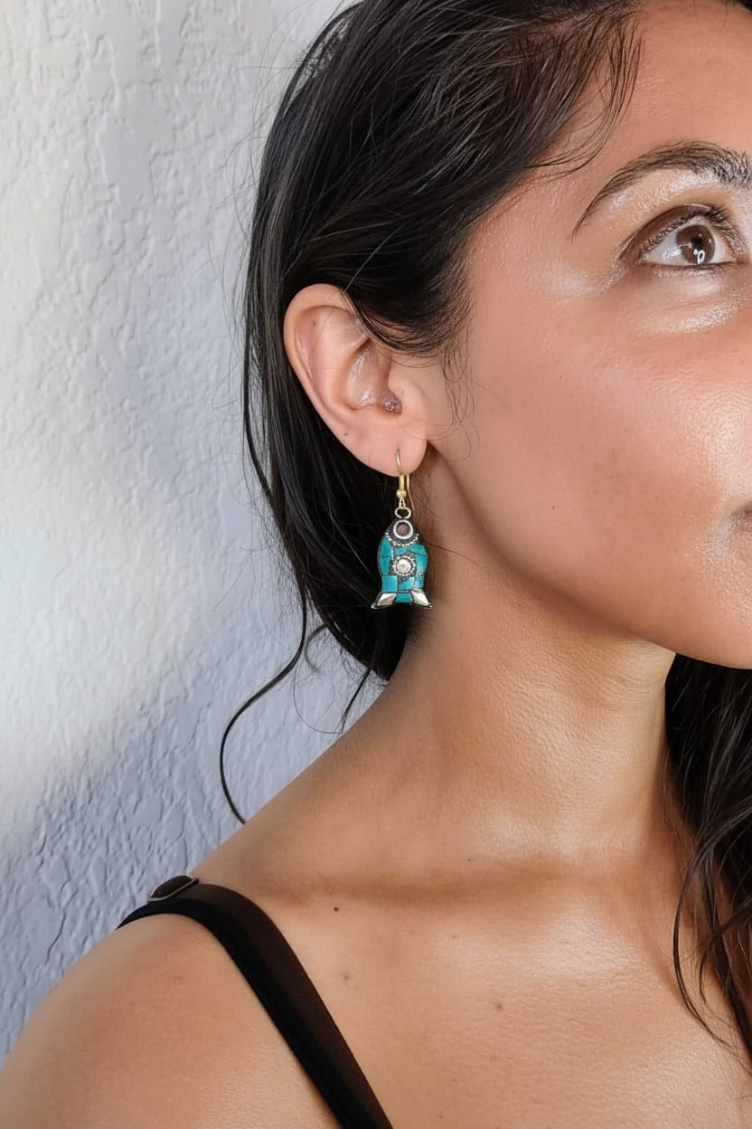 Woman wearing a turquoise earring against a white wall