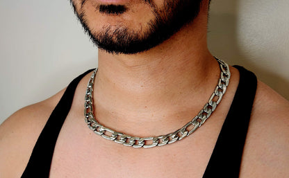 Man wearing a silver chain necklace against a neutral background