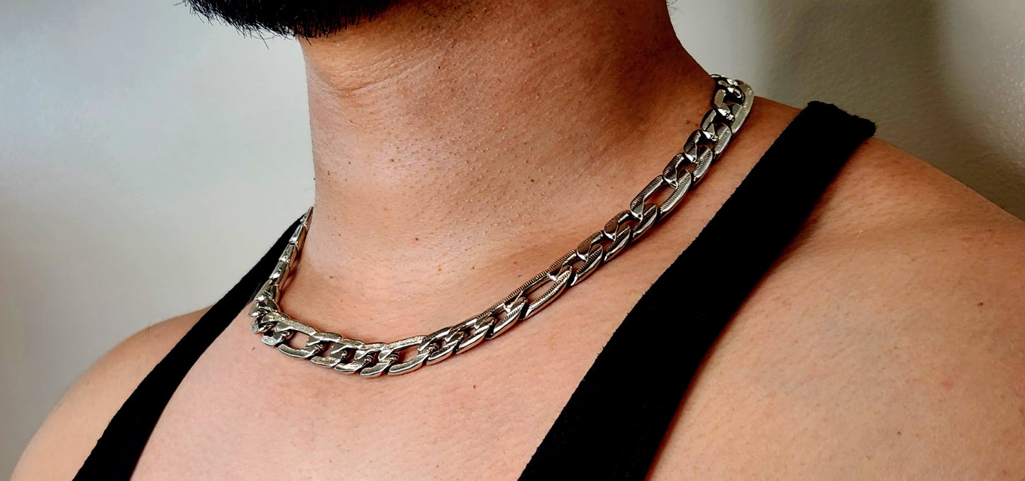 Person wearing a silver chain necklace with a plain background