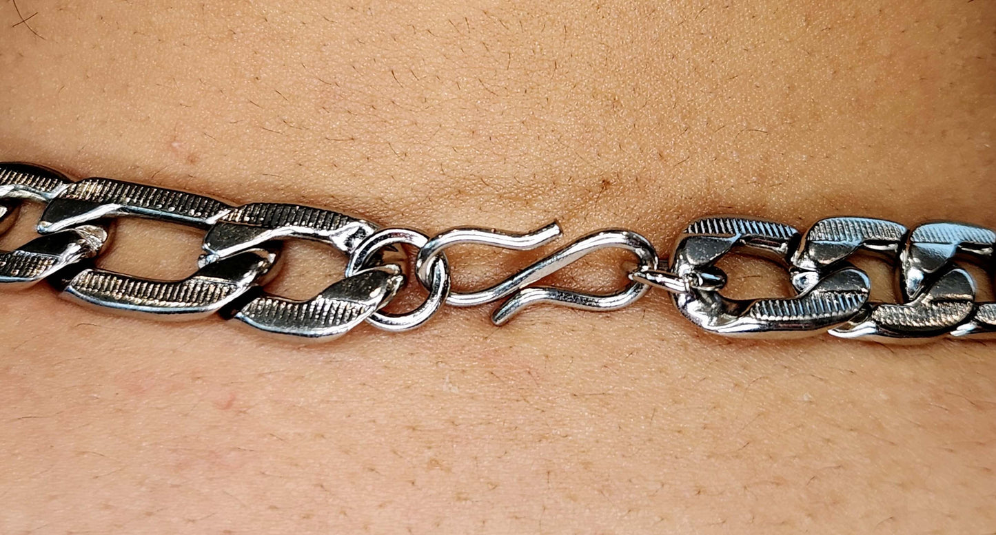 Silver chain bracelet on a person's wrist against a beige background