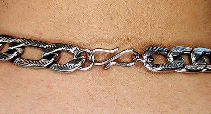 Silver chain bracelet on a person's wrist against a beige background