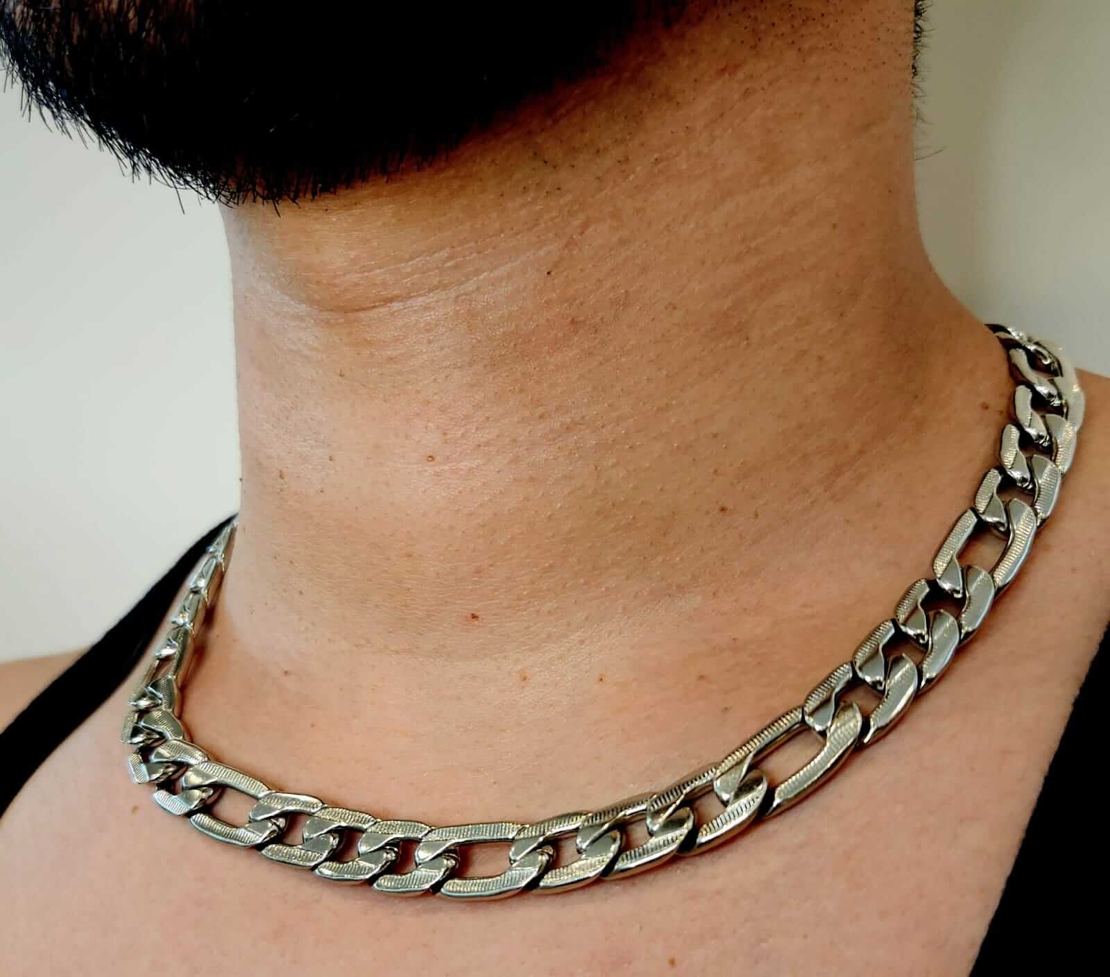 Silver chain necklace worn by a person with a neutral background
